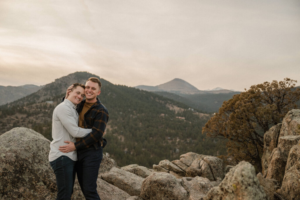 couple standing on a mountain and posing for their engagement photos