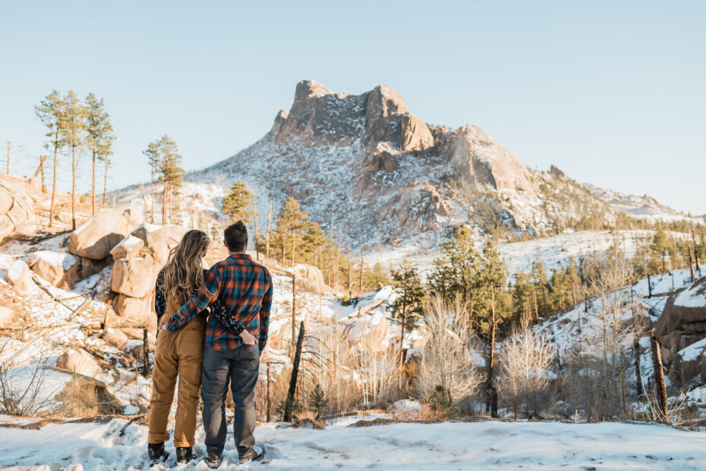 couple posing in front of a snowy mountain for their engagement photos