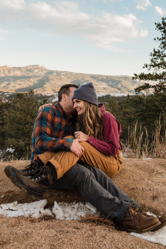 couple sitting and posing on a mountain for their engagement photos