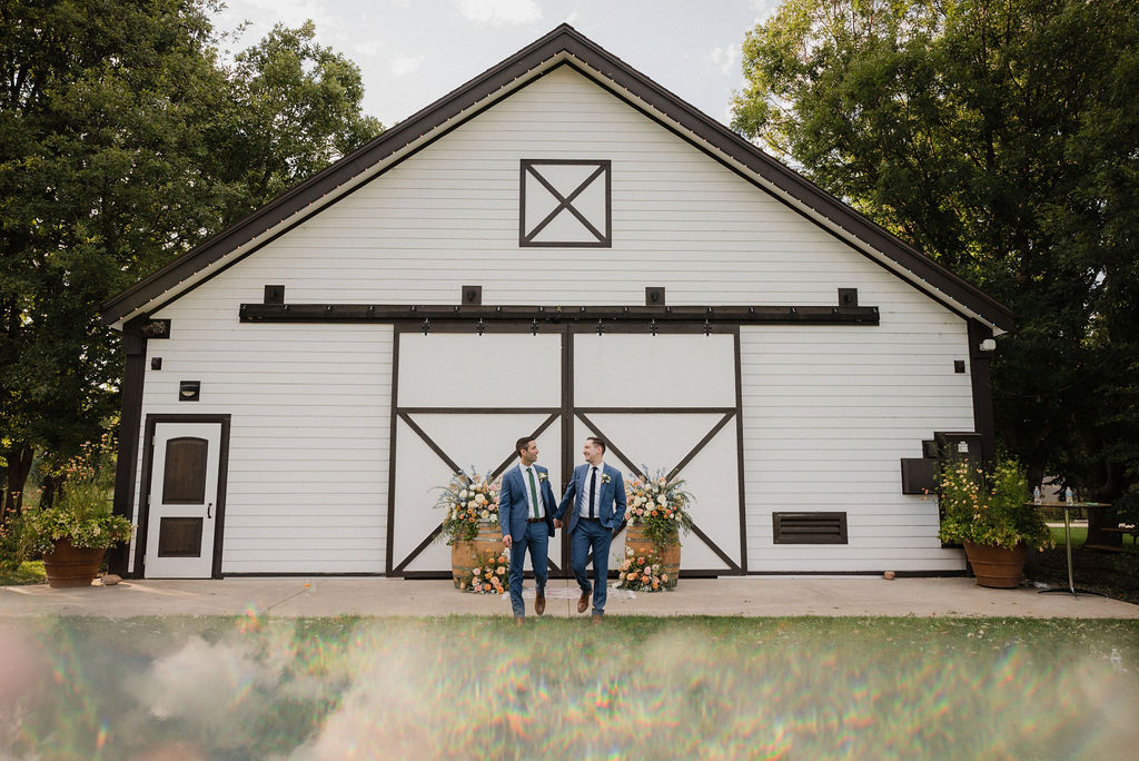 couple taking their wedding photos in front of a barn after their wedding ceremony
